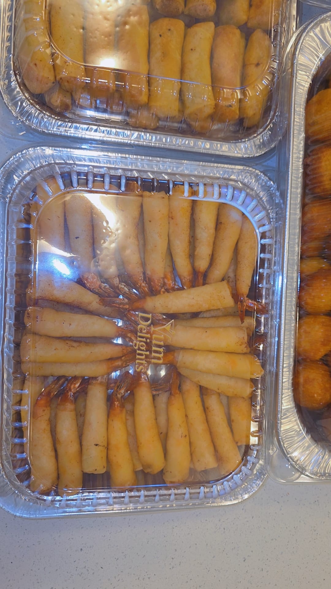 Catering trays of spring rolls and puff puff with Yum Delights branding