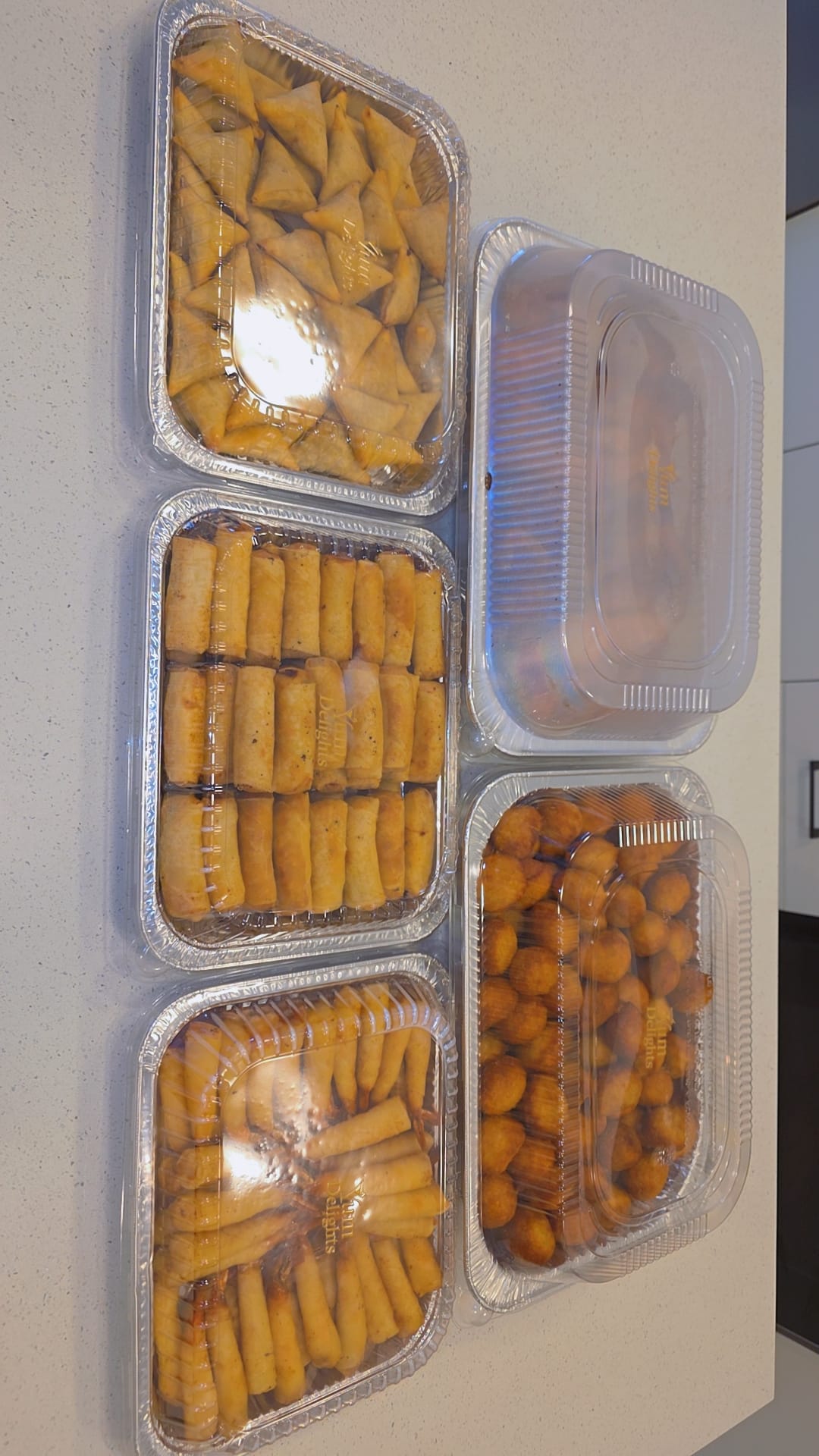 Shrimp spring rolls and finger foods in branded catering trays