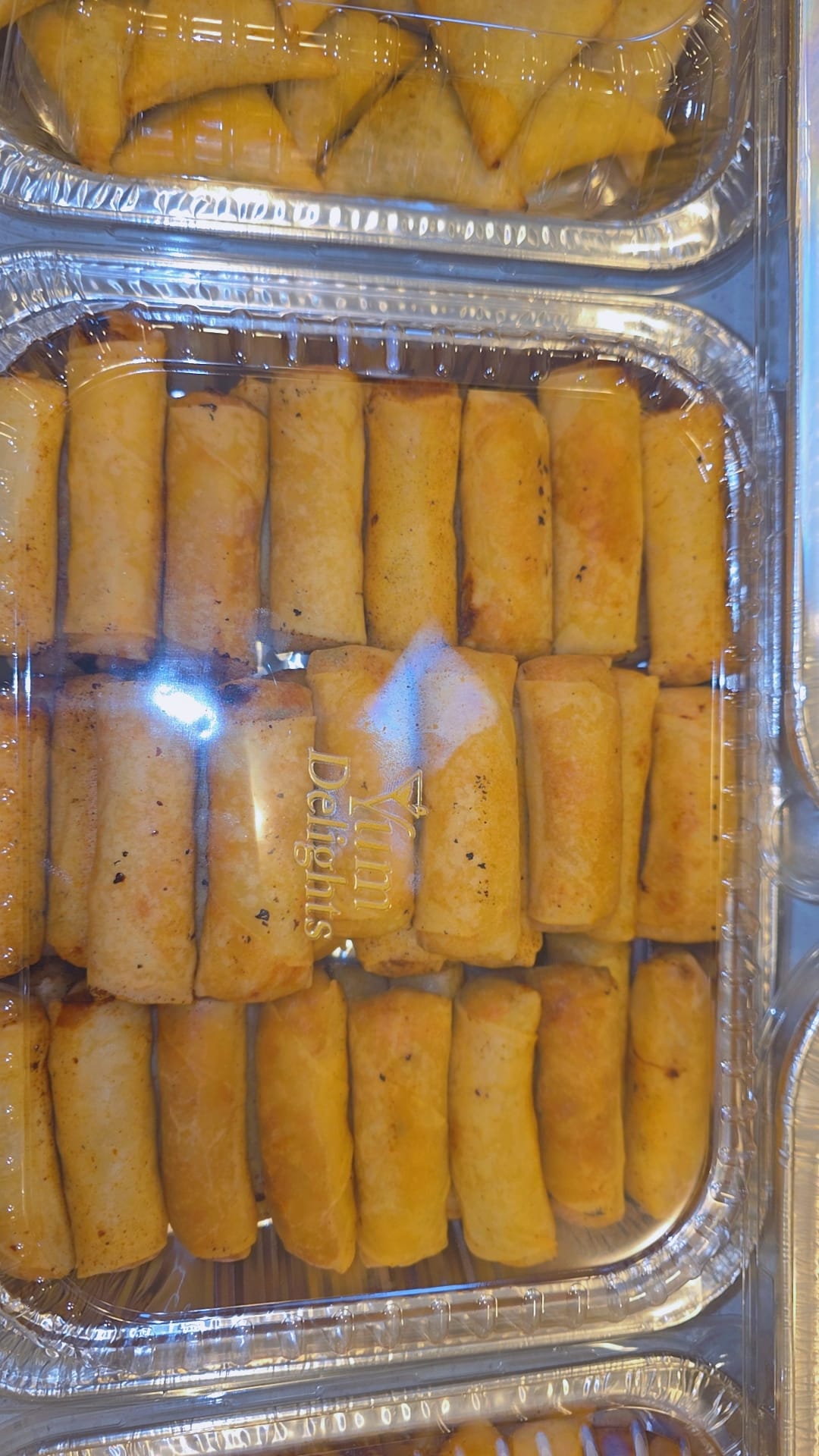Tray of samosas under branded clear lid
